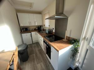 una pequeña cocina con armarios blancos y encimera en The Nest, en Keynsham