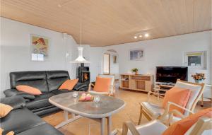 a living room with a black couch and a table at Cozy Home In Blvand With Sauna in Blåvand