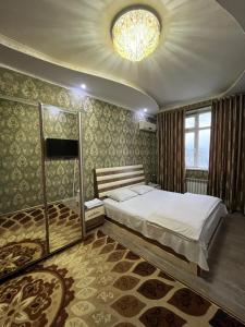 a bedroom with a large bed and a chandelier at Karabolo in Dushanbe