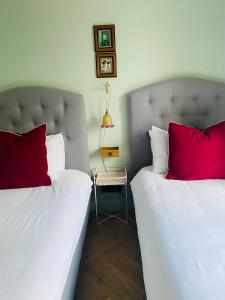 Cette chambre comprend 2 lits avec des oreillers rouges. dans l'établissement Ben A'an House, à Callander