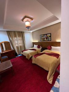 a hotel room with two beds and a red carpet at Hotel Kasbah Asmaa in Midelt