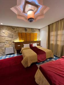 a bedroom with two beds and a stone wall at Hotel Kasbah Asmaa in Midelt