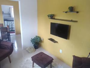sala de estar con TV de pantalla plana en una pared amarilla en MEU PONTO EM LENÇÓIS, en Lençóis