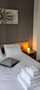 ein Bett mit weißer Bettwäsche und einer Kerze auf dem Tisch in der Unterkunft Suite Deluxe, voyages d'affaires. in Saint-Nazaire