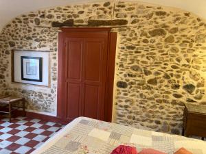 Saint-Florent-sur-AuzonnetにあるCharmant logement dans les Cevennesの石壁のベッドルーム1室、ベッド1台が備わります。