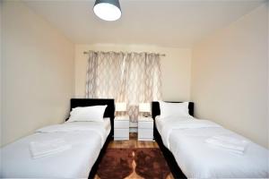 two beds in a room with a window at Spacious Two-Bedroom Apartment in Dagenham