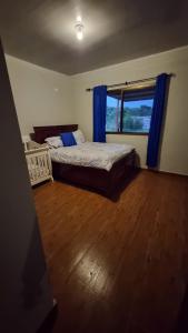 een slaapkamer met een bed en een raam met blauwe gordijnen bij Vistaverdeboquete in Boquete