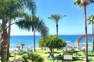 een uitzicht op een strand met palmbomen en de oceaan bij MI CAPRICHO BEACHFRONT- P301 Apartment with sea view in Mijas Costa