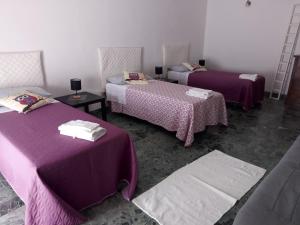 - 3 lits dans une chambre avec des draps violets dans l'établissement Shanel, à Seravezza