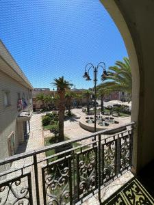 a balcony with a view of a courtyard with palm trees at Maison Umberto I a Villasimius centro in Villasimius