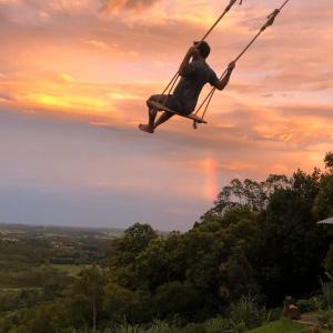 a man sitting on a swing in the sky at Pousada Refúgio das Montanhas in Praia Grande