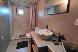 een badkamer met een wastafel, een toilet en een spiegel bij Home Of Irini in Komniná