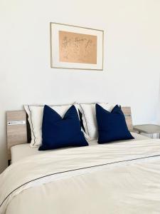 a white bed with blue pillows on top of it at Cosy apparemment in Lausanne