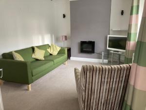 a living room with a green couch and a television at Tempest House 3 bedroom in Hartlepool