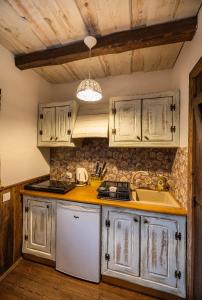 a kitchen with white cabinets and a sink at Domki Osada Werdołyna in Polańczyk