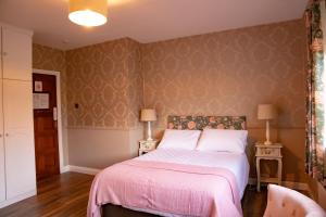 um quarto com uma cama com um cobertor rosa em The Ring Farmhouse em Birr