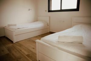 two white beds in a room with a window at Cozy Beautiful Guest House in HaZore‘im