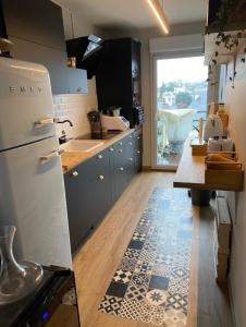 a kitchen with a white refrigerator and a tile floor at Appartement pour les 24 heures in Le Mans