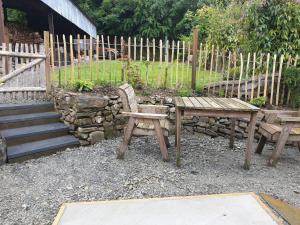 a bench and a table and a chair in a yard at Snuggle hot tub Dolgoy in Blaencelyn