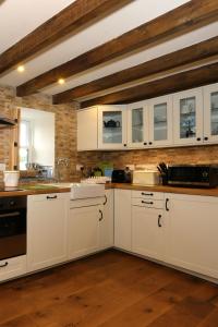 a kitchen with white cabinets and a wooden floor at Snuggle hot tub Dolgoy in Llwyn-Dafydd