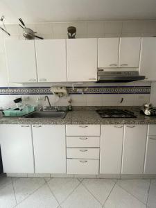 Acogedor apartamento en norte - 2 habitaciones في بوغوتا: مطبخ مع دواليب بيضاء ومغسلة