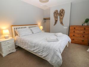 a bedroom with a large white bed and a dresser at 6 Milton Place in Bideford