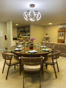 una sala da pranzo con tavolo, sedie e lampadario pendente di Casa de alto padrão em Antunes - Maragogi a Maragogi