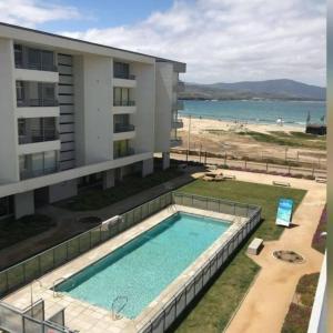 - une piscine à côté d'un bâtiment et de la plage dans l'établissement Descanso y Aire Fresco en Los Molles, à Los Molles