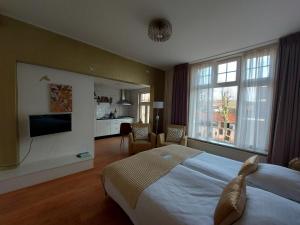 a bedroom with a large bed and a living room at Prins Appartementen in Egmond aan Zee