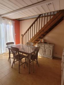 ein Esszimmer mit einem Tisch, Stühlen und einer Treppe in der Unterkunft Maison de plage in Narbonne-Plage