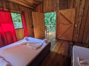 a bedroom with a bed with a door and a window at Citronela Lodge Corcovado in Drake