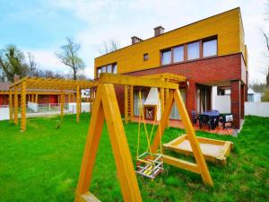 un parque infantil frente a una casa en Comfortable holiday home with a nice garden, close to the sea, Sarbinowo, en Sarbinowo