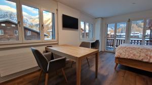 a bedroom with a table and a bed and windows at Studio direkt an der Langlaufloipe in Oberwald