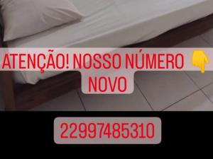 a sign that says nosos number novo on a bed at Pousada nascente do sol in Macaé