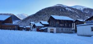 ein schneebedecktes Dorf mit Bergen im Hintergrund in der Unterkunft Studio direkt an der Langlaufloipe in Oberwald