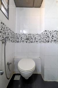 a white toilet in a bathroom with black and white tiles at Hotel Gemini in Mumbai