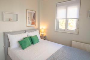 a bedroom with a white bed with two green pillows at Kima: Relaxing beach home next to sparkling waters in Nea Makri
