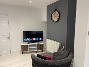 a living room with a tv and a chair and a clock at Campion lodge in Hull