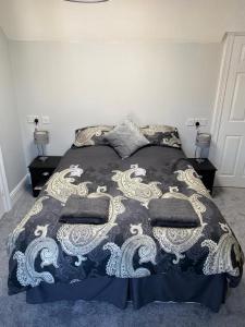 a bed with a black and white comforter and pillows at The Terrace - Annexe with views in Bathford