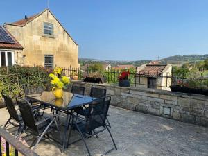 a table with chairs and a vase of flowers on a patio at The Terrace - Annexe with views in Bathford