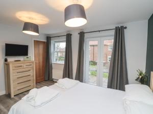 a bedroom with two white beds and a television at Rosie's Retreat in Filey