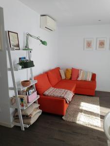 a orange couch in a living room with a ladder at Pis pràctic i agradable sobre la Marina Palamós in Palamós