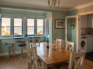 a dining room with a table and chairs and windows at 4 Victoria Court in Sheringham