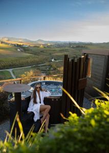 une femme assise sur une chaise à côté d'un bain à remous dans l'établissement Il GrecAle - Ristorante e camere, à La Morra