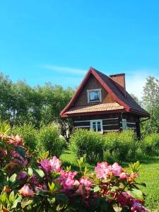 una casa con techo rojo y algunas flores en Domki Osada Werdołyna, en Polańczyk