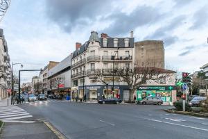 維勒蒙的住宿－MBA Splendide Appart - Le Raincy - Banlieue Paris，一条城市街道,有一座白色的大建筑,有汽车停放