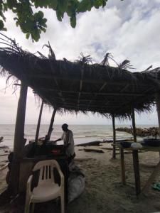 een man die onder een hut op het strand staat bij Cielito Lindo in Necoclí