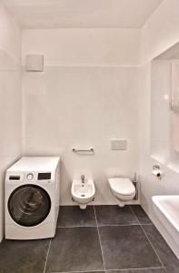 a white bathroom with a washing machine and a toilet at Rosa Apartment with parking historic city center in Merano