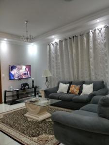 Una sala de estar con dos sofás azules y un televisor. en Casa da Thalita, en Pirenópolis
