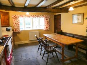 a kitchen with a wooden table and chairs at Hawkyard's Cottage in Oldham +5 photos